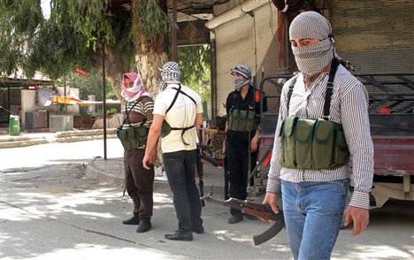 In this Friday, April 6, 2012 photo, Free Syrian Army fighters gather on a corner during fighting with Syrian troops in a suburb of Damascus, Syria.