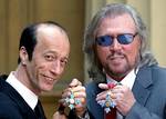 The two surviving members of the Bee Gees, Robin, left, and Barry Gibb hold their Commanders of the Order of the British Empire (CBE) decorations after receiving them from Prince Charles at Buckingham Palace, London, Thursday May 27, 2004. The third brot