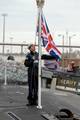 A sailor assigned to the Royal Navy submarine HMS Astute (S119) prepares to raise the flag as the ship arrives at Naval Station Norfolk.