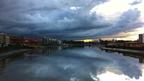 Dark grey cloud above river and buildings