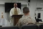 Staff Sgt. Matthew S. Thompson listens to Lt. Leo F. Arnone, a Navy chaplain, as he reads scripture during catholic mass in the chapel aboard the amphibious assault ship USS Makin Island (LHD 8).