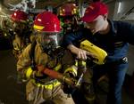 Hull Maintenance Technician Fireman Matthew Colon is instructed by Hull Maintenance Technician 1st Class Dustin Grover as a hose team combats a simulated fire.