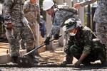 U.S. Army Spc. Danielle Robinson, center, with the 643rd Engineer Company, shovels concrete as Royal Thai Marine Corps Lt. Swat Yuneyun, right, smooths it over the foundation of a multipurpose building being constructed at the Ban Lumgoen school in Pak Tong Chai, Nakhon Ratchasima province, Thailand, Jan. 24, 2012, during exercise Cobra Gold 2012. Cobra Gold is a regularly scheduled joint/combined exercise designed to ensure regional peace and strengthen the ability of the Royal Thai Armed Force