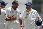 India's captain Mahendra Singh Dhoni, right, speaks with Praveen Kumar, center and Suresh Raina after beating the West Indies by 63 runs on the fourth day of their first cricket Test match in Kingston, Jamaica, Thursday June 23, 2011.