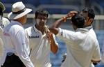 India's Praveen Kumar, second from left, looks on as umpire Daryl Harper, left, rules that he can't bowl again in the first innings, to captain Mahendra Singh Dhoni, partially covered at right, on the second day of the first cricket Test match against West Indies in Kingston, Jamaica, Tuesday June 21, 2011. Kumar was warned three times for illegal action during his bowling spell.