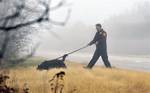 In this Dec. 5, 2011 file photo, an officer from the Suffolk County Police Department's K-9 Unit uses a dog to search through the brush along the median of Ocean Parkway, near Oak Beach in Long Island, N.Y. A year ago, the first of 10 sets of human remains were found strewn in the thicket along the seven-mile stretch of highway.