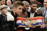 Floyd Mayweather Jr., center, poses for a photo with Justin Bieber and Yuriyorkis Gamboa after defeating Miguel Cotto for the WBA super welterweight title, Saturday, May 5, 2012, in Las Vegas.