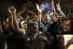 Egyptian supporters chant slogans and carry posters with pictures of presidential runoff candidate Ahmed Shafiq in front of his ransacked campaign headquarters in Cairo, Egypt Tuesday, May 29, 2012. A mob set fire late Monday to Shafiq's campaign headquarters.