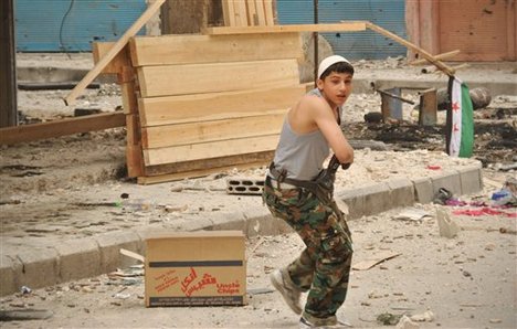 A Syrian rebel walks past destroyed shops at al-Bayada neighborhood in Homs, Syria, Thursday, May 10, 2012.