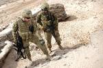 U.S. Navy Cmdr. Thomas A. Sheppard, commanding officer of Provincial Reconstruction Team Farah (right), and Lt. j.g. Brian McLean, an engineer, examine the integrity of a road during a mission in Farah province, Afghanistan, May 9. PRT Farah is a unit of soldiers, sailors and airmen working with various government and non-government agencies tasked with facilitating governance and stability in the region by working hand in hand with local officials and the government of the Islamic Republic of A