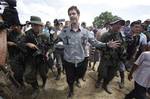 French journalist Romeo Langlois, center, is escorted by rebels of the Revolutionary Armed Forces of Colombia, FARC, upon their arrival to San Isidro, southern Colombia, Wednesday, May 30, 2012. Langlois , who was taken by rebels on April 28 when they attacked troops he was accompanying on a cocaine-lab eradication mission, was handed over by the rebels to a delegation that included a French diplomat in San Isidro.