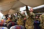 Aboard a commercial airliner, paratroopers with the 82nd Airborne Division’s 1st Brigade Combat Team stow carry-on baggage into overhead bins as they prepare to depart Fort Bragg, N.C., for a deployment to Afghanistan March 21, 2012. The closer they get to the combat zone, the more militarized their travel will become. (U.S. Army photo by Sgt. Michael J. MacLeod)