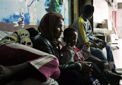 File - African refugees sit in the hallway of a shelter in Tel Aviv, in this photo taken Monday, Feb. 25, 2008.