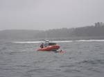 RYE, N.H. A 25-foot boat crew from Coast Guard Station Portsmouth Harbor approach one of three men to rescue him from 57-degree water about a mile off the coast of Rye, N.H., Friday, June 24, 2011. The men were knocked in the water after a wave came over the stern of their 18-foot boat and capsized it when they were recreational lobstering. Photo courtesy of the New Hampshire Fish and Game. (1296220) ( U.S. Coast Guard rescues 3 from cold water after boat capsizes )