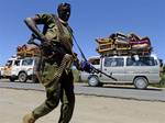 File - Somalis with their luggage loaded onto mini-vans leave Elasha corridor as an African Union peacekeeping soldier from Burundi patrolling on foot during clashes with Islamist militants in Elasha district in Somalia Friday, May 25, 2012.