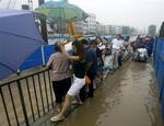 In this Tuesday, July 13, 2010 photo released by China's Xinhua News Agency, people wade a waterlogged street in Wuhan, capital of central China's Hubei Province.