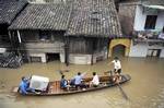 In this Thursday June 24, 2010 photo released by China's Xinhua news agency, local residents transfer their belongings on a boat in Xiangtan county, in central China's Hunan province.