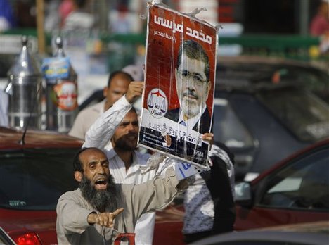 Egyptian supporters of Muslim brotherhood candidate Mohammed Morsi hold a poster with Arabic that reads, "'Mohammed Morsi, president for Egypt" in Tahrir Square, Cairo, Egypt, June 18, 2012.