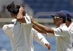 India's Ishant Sharma, left, is congratulated by teammate Rahul Dravid after taking the wicket of West Indies' batsman Ravi Rampaul, who was caught behind for 34 runs, in the second innings during the fourth day of their first cricket Test match in Kingston, Jamaica, Thursday, June 23, 2011.