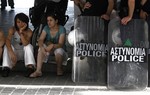 Athens Municipality contract workers sit by police officers during a protest outside from the finance ministry in Athens, Thursday, June 14, 2012.