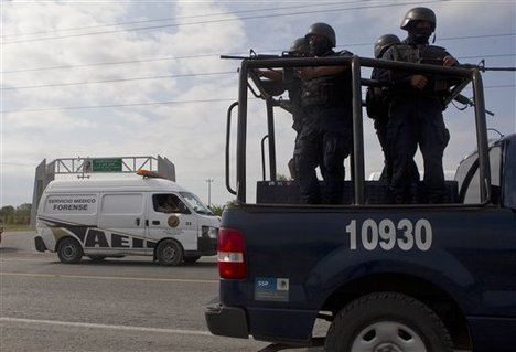 Federal police on a vehicle guard one of the three forensic trucks where several bodies were placed after dozens of bodies, some of them mutilated, were found on a highway connecting the northern Mexican metropolis of Monterrey to the U.S. border found in the Km 47 of the Reynosa-Cadereyta road in the town of San Juan near the city of Monterrey, Mexico, Sunday, May 13, 2012.