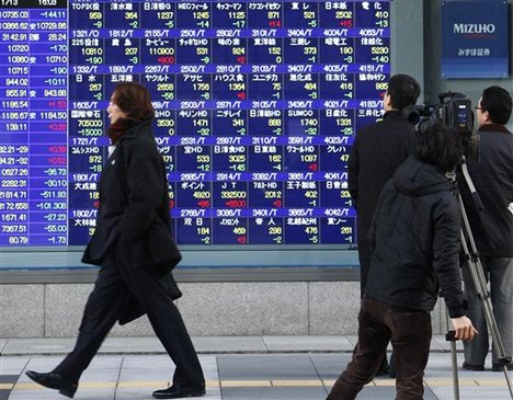 In this Jan. 13, 2010 photo, a TV cameraman films an electric stock board indicating the benchmark Nikkei 225 stock average lost 144.11 points, or 1.3 percent, to 10,735.03 while passersby check the share prices in Tokyo, Japan. Dominique Strauss-Kahn, the managing director of the International Monetary Fund, says in Tokyo, Monday, Jan. 18, 2010, that China and other developing Asian economies are leading a global recovery that is faster and stronger than expected, but warned that money rushing into emerging markets could lead to asset bubbles. (AP Photo/Shizuo Kambayashi)