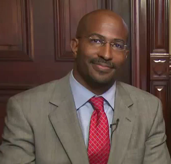 Portrait photo of an African-American man seated in front of a wood paneled wall. He has a bald head, glasses and a mustache, and is wearing a gray suit, blue shirt and red tie.