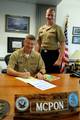 Seaman James Vidal gives Master Chief Petty Officer of the Navy (MCPON) Rick West the 2009 Combined Federal Campaign donation forms to fill out.