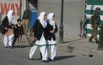 School students walk as Indian paramilitary troopers removing the concertina wire from the bunker before its removal in Srinagar, the summer capital of Indian Kashmir. 20, April, 2012.