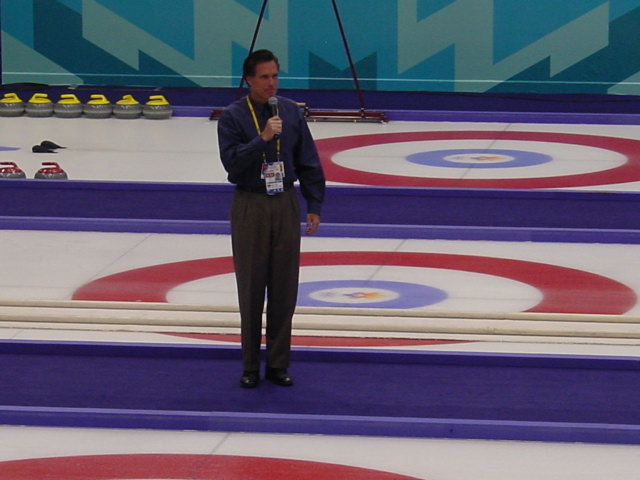 Photograph of Romney standing with microphone in middle of curling lanes