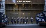 Riot police stand guard in front of a branch of the recently nationalized bank during a protest in Madrid, Spain, Monday, May 14, 2012.