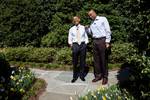 President Barack Obama laughs with Clark Kellogg as they walk through Children's Garden to the White House basketball before an interview for the CBS 