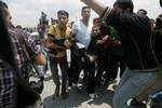 Palestinian protesters carry away a wounded demonsrator after Israeli soldiers opened fire during a massive march towards the Erez border crossing in the northern Gaza Strip on May 15, 2011 to mark the 