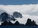 Fort Point from Brans field Strait, with St. Kiprian Peak and Lyutitsa Nunatak in the background. Fort Point is a conspicuous rocky point rising to 85 m and linked by a low 700 m isthmus to the southeast coast of Greenwich Island in the South Shetland Islands, Antarctica.