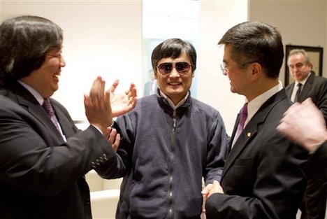 In this photo released by the US Embassy Beijing Press Office, blind lawyer Chen Guangcheng, center, holds hands with U.S. Ambassador to China Gary Locke, right, as U.S. State Department Legal Advisor Harold Koh, left, applauds, before leaving the U.S. embassy for a hospital in Beijing Wednesday May 2, 2012.