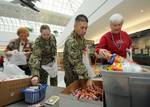 Machinist Mate 1st Class Patricia Atterberry and Machinist Mate 1st Class Pablo M. Esquivel help members of the USO put together bags of treats at Baltimore Washington International Airport for Sailors returning from overseas duty assignments.