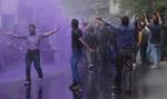 Kashmiri government employees shout anti government slogans as Indian police spray purple colored water to disperse a protest demanding an increase in the retirement age from 58 to 60 and the release of arrears,in Srinagar on June 13, 2012. Indian police detained dozens of government employees, used water cannons and resorted to baton charging the employees during the protest the employees started a fresh phase of agitation under which civil Secretariat would be encircled on three days while a c