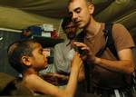 U.S. Army 1st Lt. Tory Marcon, assigned to the 212th MASH unit, helps a Pakistani child drink a powered milkshake from a Meals Ready-to-Eat (MRE) in Muzaffarabad, Pakistan.