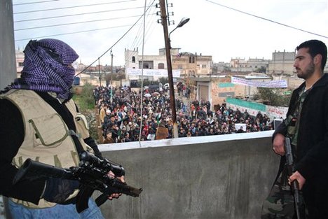 Syrian army defectors stand guard on a rooftop to secure an anti-Syrian regime protest in the Deir Baghlaba area in Homs province, central Syria, on Friday, Jan. 27, 2012. Armed forces loyal to President Bashar Assad barraged residential buildings with mortars and machine-gun fire, killing at least 30 people, including a family of women and children during a day of sectarian killings and kidnappings in the besieged Syrian city of Homs, activists said Friday. (AP Photo)