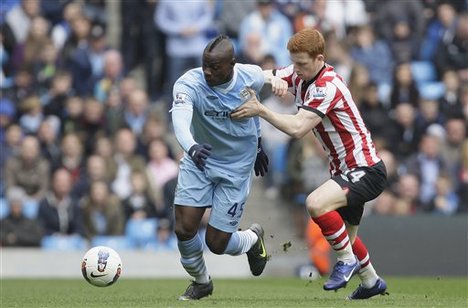 Manchester City's Mario Balotelli, center, fights for the ball against Sunderland's Jack Colback during their English Premier League soccer match at The Etihad Stadium, Manchester, England, Saturday, March 31, 2012.