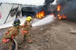 Guernsey, Wyo. (Oct. 22, 2002) -- Platte County Volunteer Firefighters Rob Niemczyk (left) and Bob Wilhelm man a 2-inch fire hose and spray down a simulated motor vehicle accident with foam during the opening phase of Diligent Warrior 2003. Diligent Warrior is a nuclear weapons accident training exercise directed by the Office of the Secretary of Defense (OSD) and sponsored by the Defense Threat Reduction Agency (DTRA) to ensure the readiness of military, federal, state, and local response agenc