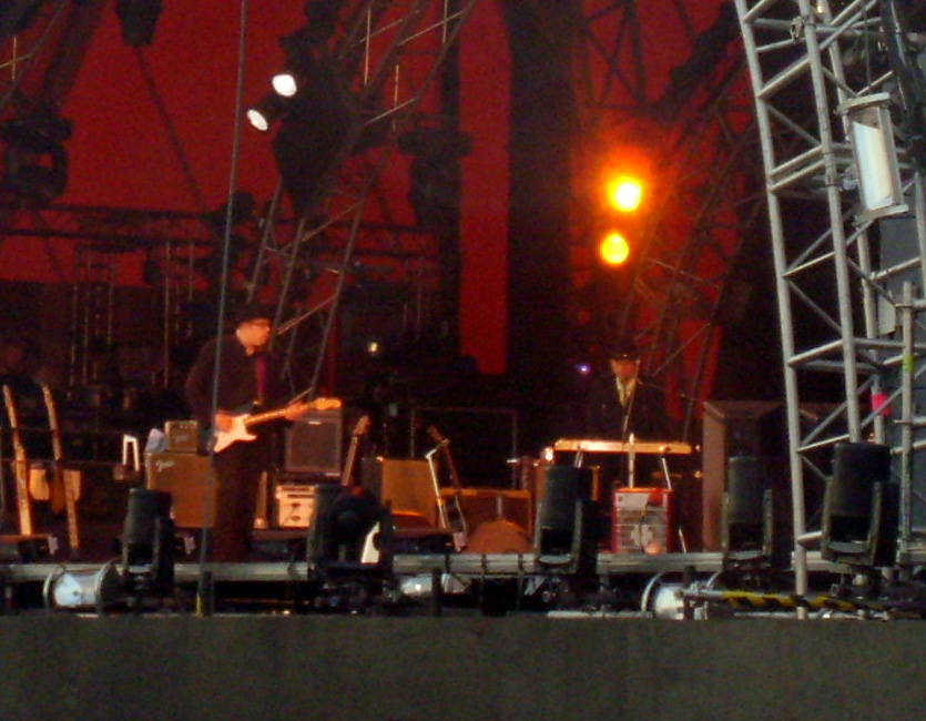 Dylan, standing and playing the keyboards, onstage with members of his band.