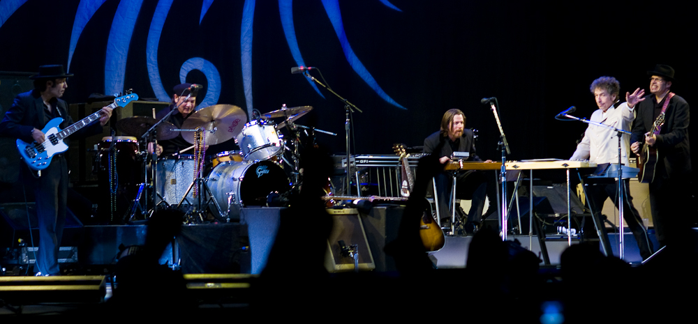 Dylan together with five members of his band onstage. Dylan, dressed in a white shirt and black pants, is second from right.