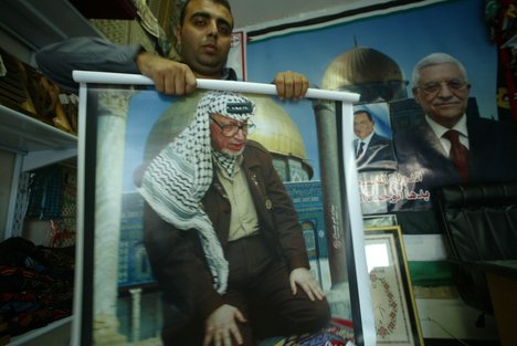 File - A shopkeeper rolls ups a large poster of Yasser Arafat in the  Gaza Strip, Palestinian territories.