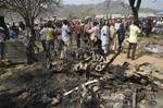 In a Sunday, Dec. 25, 2011 file photo, onlookers gather around a car destroyed in a blast next to St. Theresa Catholic Church in Madalla, Nigeria after an explosion ripped through a Catholic church during Christmas Mass near Nigeria's capital Sunday, killing scores of people, officials said.