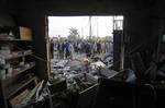 People gather around a destroyed shop at the scene of a car bomb attack in Baghdad, Iraq, Thursday, Jan. 27, 2011. A car bomb ripped through a funeral tent in a mainly Shiite area of Baghdad on Thursday, killing and wounding scores of people and prompting scuffles between police and Iraqis angry about security failures.