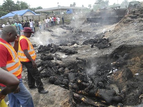 People look at charred bodies following fuel tanker explosion in Okogbe near Port Harcourt Nigeria, Thursday, July 12, 2012.