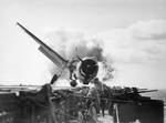 Crash landing of F6F-3, Number 30 of Fighting Squadron Two (VF-2), USS Enterprise, into the carrier's port side 20mm gun gallery, 10 November 1943. Lieutenant Walter L. Chewning, Jr., USNR, the Catapult Officer, is climbing up the plane's side to assist the pilot from the burning aircraft.