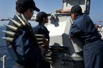 Sailors load a Mk 38 Mod 2 25mm machine gun system aboard amphibious dock landing ship USS Pearl Harbor (LSD 52).