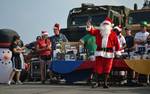 Chief Damage Controlman Alan Vanmarter, dressed as Santa Claus, passes out gifts during a holiday gift event for Sailors and Marines aboard the amphibious dock landing ship USS Whidbey Island (LSD 41).